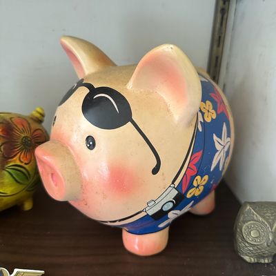 Novelty ceramic piggy bank featuring a tourist pig wearing sunglasses, a floral shirt, and a camera, shown in good vintage condition.