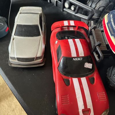Vintage Nikko red Dodge Viper radio-controlled car alongside a silver Mercedes-style RC car, displaying light dust and wear.