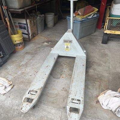Heavy-duty manual pallet jack with a 5,500 lb capacity, showing surface wear and paint loss consistent with garage or warehouse use.