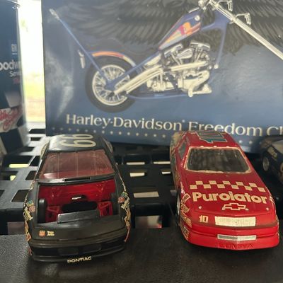 Vintage plastic scale model NASCAR stock cars displaying wear, alongside a Revell Harley-Davidson Freedom Chopper model box.
