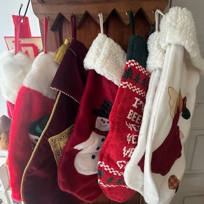 Collection of assorted plush, velvet, and knit Christmas stockings hanging from a wooden rack.