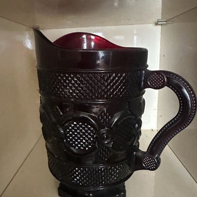 Vintage dark ruby red pressed glass pitcher featuring a diamond point and circle pattern on a pedestal base.