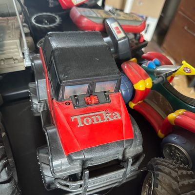 Vintage Tonka red and black plastic 4x4 monster truck alongside other vintage toy vehicles.