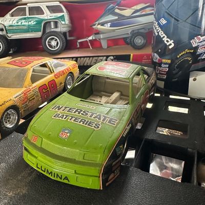 Vintage plastic and die-cast toy NASCAR stock cars, featuring a green #18 Interstate Batteries Chevrolet Lumina model, alongside a boxed...