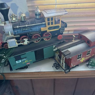 Vintage plastic and metal Denver Express toy train locomotive with green freight car and red Santa Fe caboose.