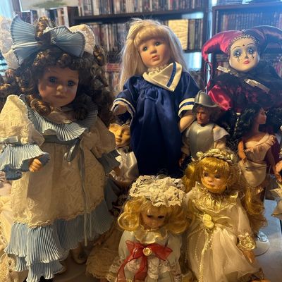 Collection of vintage porcelain and collectible dolls featuring intricate dresses, blonde hair, and themed costumes, including a...