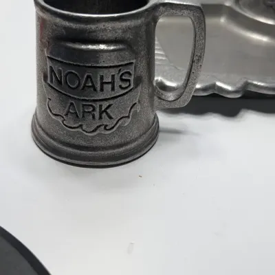 Sale Photo Thumbnail #210: The Vintage Pewter Noah's Ark Mug & Plate Set by York Metal (1977) is a classic child's dinnerware set. The divided tray measures approximately 10" x 8" shaped as the Ark, and the 3" mug often features the alphabet or Noah's Ark graphics.