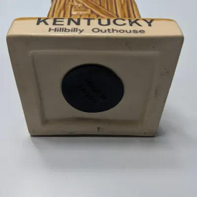 Sale Photo Thumbnail #105: The vintage "Kentucky Hillbilly Outhouse" ceramic coin bank is a popular mid-to-late 20th-century novelty travel souvenir. These campy, kitschy collectibles were mass-produced in Taiwan primarily during the 1970s and 1980s for tourist gift shops across Am