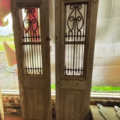 Sale Photo Thumbnail #514: Up for sale is an impressive pair of rustic architectural doors featuring decorative turned wrought iron scroll grilles and hinged inner ventilation frames. 

These classic Mediterranean / French Country / Spanish Colonial style doors work exceptionally w