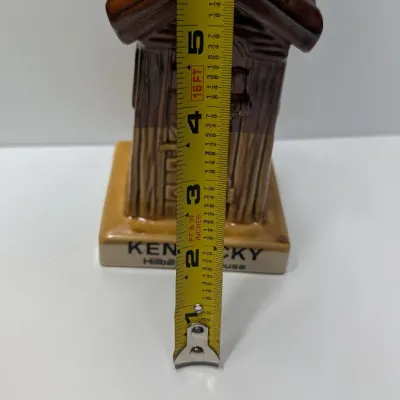 Sale Photo Thumbnail #106: The vintage "Kentucky Hillbilly Outhouse" ceramic coin bank is a popular mid-to-late 20th-century novelty travel souvenir. These campy, kitschy collectibles were mass-produced in Taiwan primarily during the 1970s and 1980s for tourist gift shops across Am