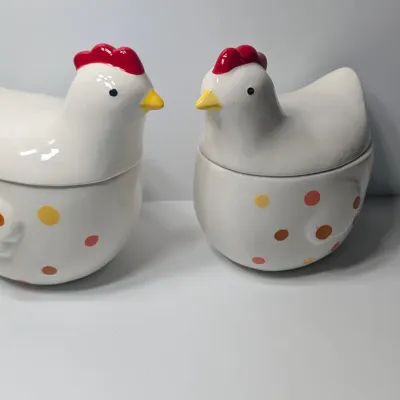 Sale Photo Thumbnail #133: The TAG (often sold as Tag Kitchen) Polka Dot Chicken Covered Nesting Candy Dishes feature a whimsical, dual-compartment design. Made of ceramic, these brightly colored lidded bowls measure roughly 5 inches long and 6.5 inches tall, making them ideal coun