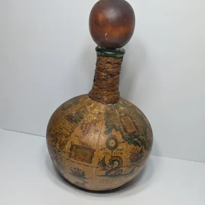 Sale Photo Thumbnail #21: Vintage 1960s leather-wrapped world map bottles are iconic mid-century barware collectibles. Most were handcrafted in Italy (particularly Florence) as decorative decanters for wine or liquor

Materials: Green or brown glass bottles encased in genuine, hea
