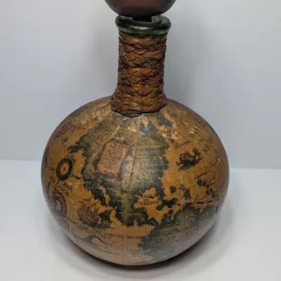 Sale Photo Thumbnail #22: Vintage 1960s leather-wrapped world map bottles are iconic mid-century barware collectibles. Most were handcrafted in Italy (particularly Florence) as decorative decanters for wine or liquor

Materials: Green or brown glass bottles encased in genuine, hea