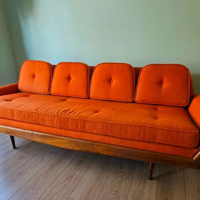 MCM Adrian Pearsall-style Gondola Sofa in Vibrant Textured Orange Fabric with Walnut Wood Accents.