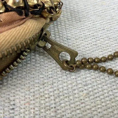 Sale Photo Thumbnail #342: Coin purse is attributed to Whiting & Davis and features a gold-tone mesh construction accented with gold beading and a secure zipper closure. The interior is lined with complimentary pink fabric. The piece measures approximately 4" H x 5" W x 1/4" D.....
