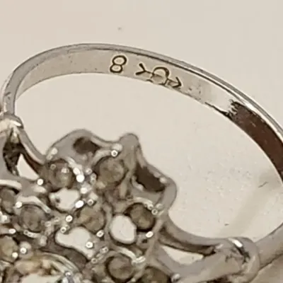 Sale Photo Thumbnail #6: This is a stunner! The photos do not do it justice. 1930s era 
Uncas International silver tone and rhinestone art deco ring. Size 8.5.

Excellent condition, marked inside with Uncas lo