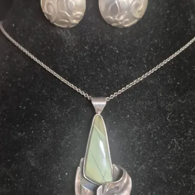 Sale Photo Thumbnail #151: Custom studio Pendant w/sterling chain & Sterling moon Earrings set



> Pendant is modernist with Green Ribbon Jasper .....wrapped within Sterling scrolls.

> Suggests this is a Vintage studio piece from 1960s/70s.....by independent artisan following

th