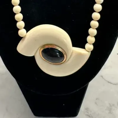 Sale Photo Thumbnail #365: vintage Crown Trifari "hurricane" pendant necklace featuring a white lucite swirl design and a gold-tone accent.
excellent condition, rare to find, overall 16" length.
no damage, chips or repairs......as is original
