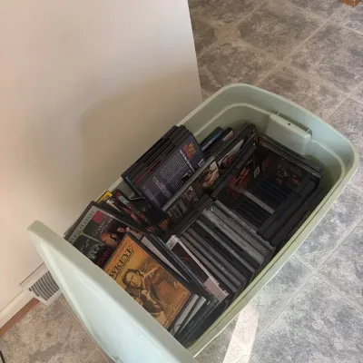 Large mixed-media entertainment lot featuring a variety of DVDs and VHS tapes, including drama, acti