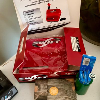 Sale Photo Thumbnail #376: Lot includes Portable king size cigarette machine. New in original box, in perfect condition. Boxes of rolling papers and hard case included.