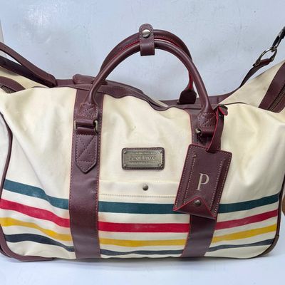 Sale Photo Thumbnail #3: Pendleton Glacier National Park canvas travel bag featuring an ivory body accented with burgundy trim and the iconic multi-color Glacier stripe pattern. Has a telescopic handle and wheels for ease of use. Like-new condition, looks to be sized for carry-on