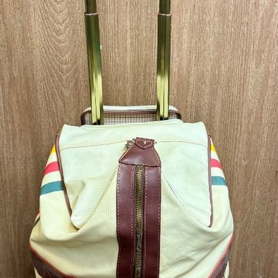 Sale Photo Thumbnail #7: Pendleton Glacier National Park canvas travel bag featuring an ivory body accented with burgundy trim and the iconic multi-color Glacier stripe pattern. Has a telescopic handle and wheels for ease of use. Like-new condition, looks to be sized for carry-on