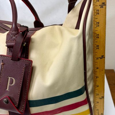 Sale Photo Thumbnail #5: Pendleton Glacier National Park canvas travel bag featuring an ivory body accented with burgundy trim and the iconic multi-color Glacier stripe pattern. Has a telescopic handle and wheels for ease of use. Like-new condition, looks to be sized for carry-on