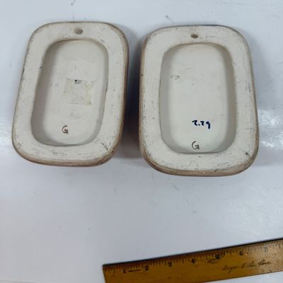 Sale Photo Thumbnail #62: Pair of ceramic plaques made to look like a wood plaque with a small woven southwestern basket.  Each is about the size of a standard light switch, good condition.