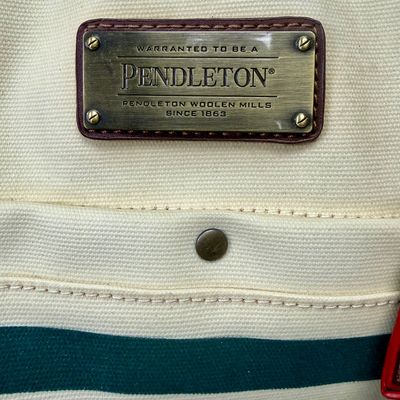 Sale Photo Thumbnail #2: Pendleton Glacier National Park canvas travel bag featuring an ivory body accented with burgundy trim and the iconic multi-color Glacier stripe pattern. Has a telescopic handle and wheels for ease of use. Like-new condition, looks to be sized for carry-on