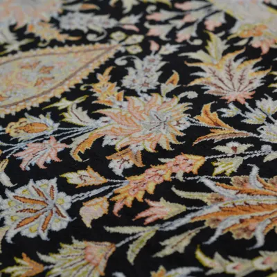 Close-up of intricate floral rug with black background and multicolor botanical details