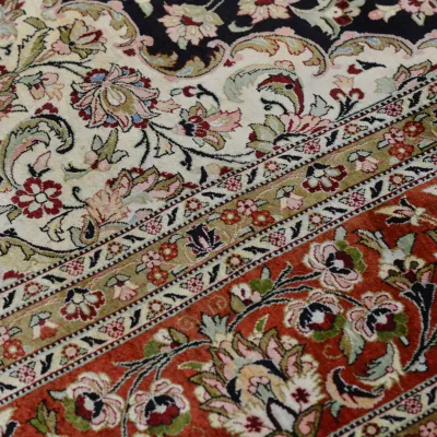 Close-up of traditional floral rug with ivory, red, black, and gold detailing