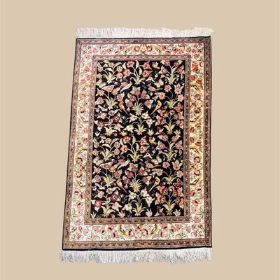 Small black and ivory traditional rug with colorful floral pattern and fringe