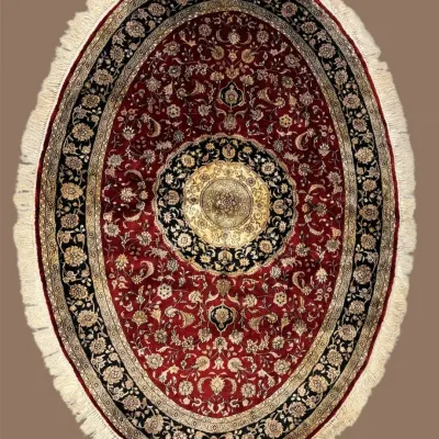 Oval burgundy traditional rug with ornate floral medallion and fringed edge