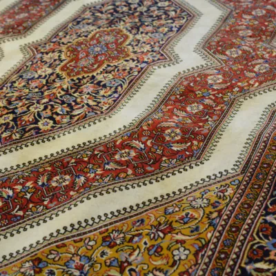 Detailed traditional rug featuring flowing floral patterns in red, ivory, gold, and navy