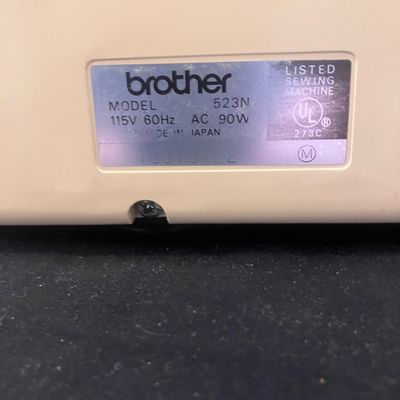 Sale Photo Thumbnail #1148: BROTHER MODEL 523N OVERLOCK SEWING MACHINE/SERGER MADE IN JAPAN. INCLUDES FOOT PEDAL, POWER CORD, SPOOLS OF THREAD, STENCIL TEMPLATE, MANUALS, AND MORE. PRE-OWNED CONDITION WITH LIGHT SURFACE WEAR.