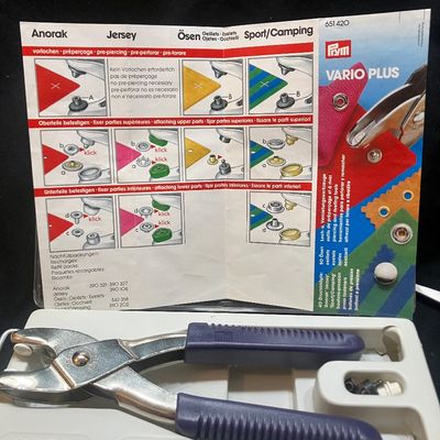 Sale Photo Thumbnail #1267: PRYM VARIO PLUS SNAP FASTENER AND EYELET PLIER KIT. INCLUDES VARIO PLIERS, ASSORTED SNAPS, EYELETS, ATTACHMENTS, INSTRUCTIONS, AND MORE. LIGHTLY USED CONDITION IN ORIGINAL PLASTIC CASE.