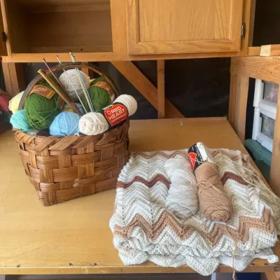 Knitting Needs With Basket Of Yarn And Almost Finished Blanket