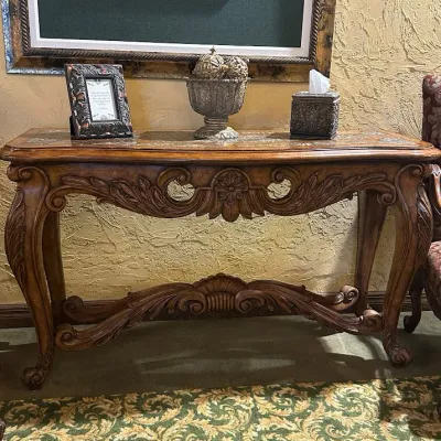 Sale Photo Thumbnail #155: Substantial traditional console table featuring extensive carved scroll and leaf detailing, shaped legs, and a decorative lower stretcher. Rich wood finish and architectural styling make this an attractive foyer, sofa, or hallway piece. 58"wx20"d*33.5h