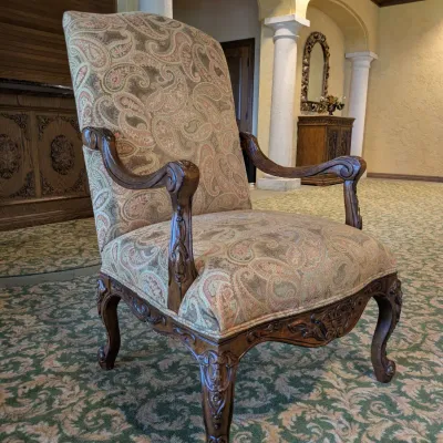 Sale Photo Thumbnail #137: High-back traditional armchair upholstered in a soft neutral paisley textile with carved wood arms, decorative apron, and cabriole-style legs. Attractive occasional chair with a more subdued palette than many of the clubhouse furnishings.