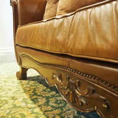 Sale Photo Thumbnail #104: Large traditional sofa upholstered in warm brown leather with oversized rolled arms, nailhead trim, carved wood base, and decorative scroll detailing. Includes coordinating oversized accent pillows and attractive aged character. 91w*38 deep* 41h