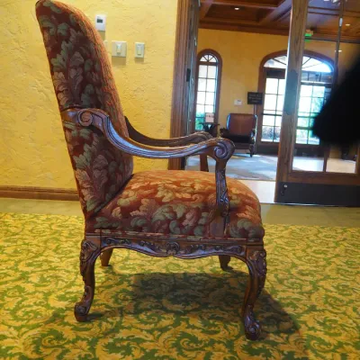 Sale Photo Thumbnail #112: Traditional high-back accent chair featuring richly patterned burgundy and muted green upholstery, carved wood arms, decorative apron, and cabriole-style legs. Substantial decorator-quality chair with classic Old World styling.