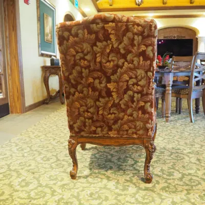 Sale Photo Thumbnail #113: Traditional high-back accent chair featuring richly patterned burgundy and muted green upholstery, carved wood arms, decorative apron, and cabriole-style legs. Substantial decorator-quality chair with classic Old World styling.