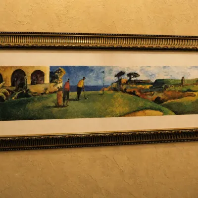 Sale Photo Thumbnail #80: Wide panoramic golf scene featuring golfers on a dramatic course surrounded by rugged landscape and architectural elements. Unusual horizontal format with professional matting and a substantial decorative frame. 65*26