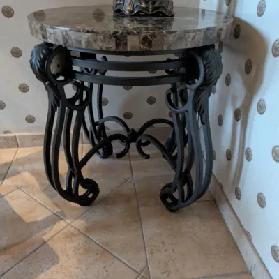 Sale Photo Thumbnail #22: Round accent table featuring a polished stone or marble-style top over an ornate black iron base with sculptural leaf and scroll detailing. A substantial decorator piece with strong Mediterranean styling. 23" round