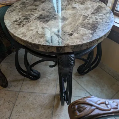 Sale Photo Thumbnail #23: Round accent table featuring a polished stone or marble-style top over an ornate black iron base with sculptural leaf and scroll detailing. A substantial decorator piece with strong Mediterranean styling. 23" round