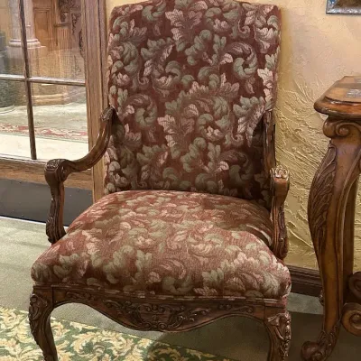 Sale Photo Thumbnail #114: Traditional high-back accent chair featuring richly patterned burgundy and muted green upholstery, carved wood arms, decorative apron, and cabriole-style legs. Substantial decorator-quality chair with classic Old World styling.