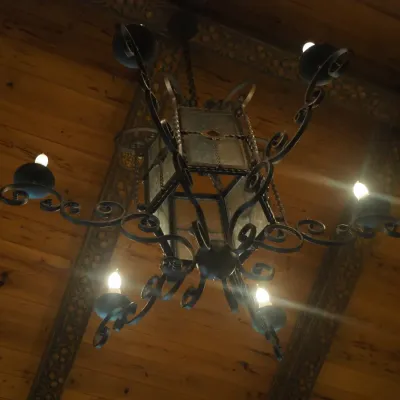 Sale Photo Thumbnail #124: Substantial Old World chandelier combining a central lantern with multiple scrolling candelabra arms. Ornate iron construction and dramatic scale make this an impressive foyer, dining, or great-room fixture. One of three coordinating fixtures available. B