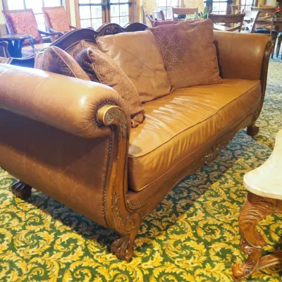 Sale Photo Thumbnail #103: Large traditional sofa upholstered in warm brown leather with oversized rolled arms, nailhead trim, carved wood base, and decorative scroll detailing. Includes coordinating oversized accent pillows and attractive aged character. 91w*38 deep* 41h