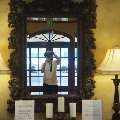 Sale Photo Thumbnail #118: Large formal wall mirror featuring an extensively carved Baroque-inspired frame with elaborate scrolling foliage and dramatic crest detail. Heavy, substantial statement piece formerly displayed above the clubhouse entry console. 41"w*58"h