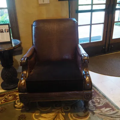 Sale Photo Thumbnail #102: Popular Designer Paul Robert traditional lounge chair featuring richly textured crocodile-embossed upholstery, oversized rolled and carved arms, decorative wood trim, and carved feet. Dramatic executive-club styling with visible character from previous us